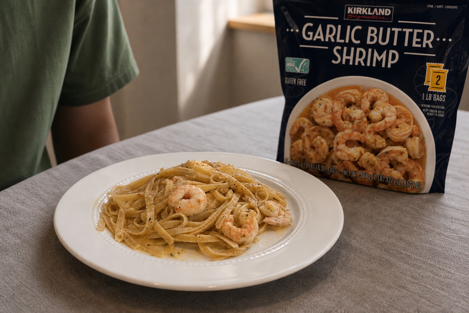 A plate of garlic butter shrimp pasta beside a Kirkland Signature Garlic Butter Shrimp package