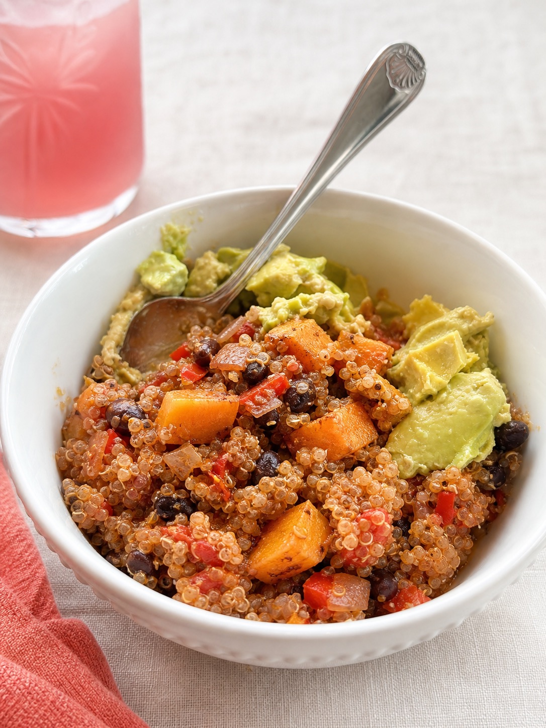 A bowl of black bean, sweet potato, and quinoa bake topped with sliced avocado